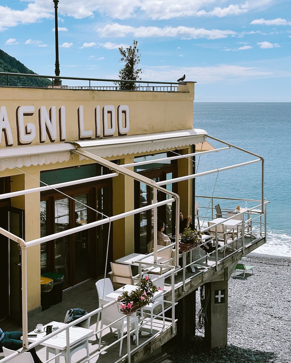 White tables and chairs at a beachside restaurant overlooking the beach in Camogli