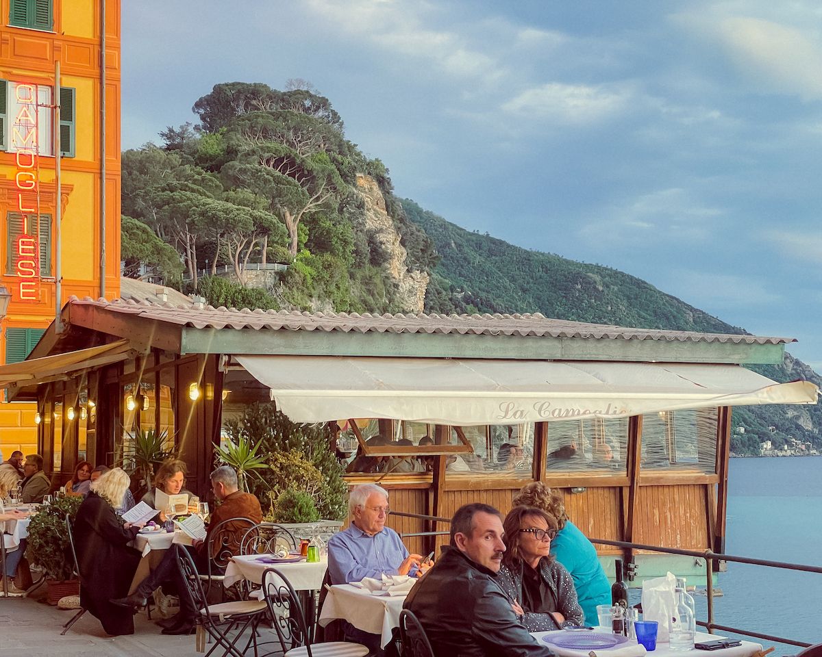 People sitting outside and dining along the beachfront pedestrian street in Camogli