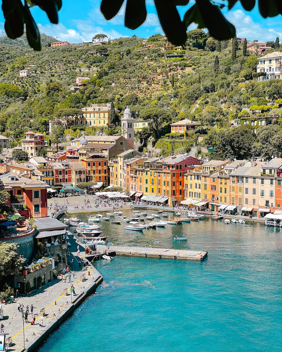 View from up high of Portofino's turquoise waterfront, boats and pastel orange, yellow and peach buildings