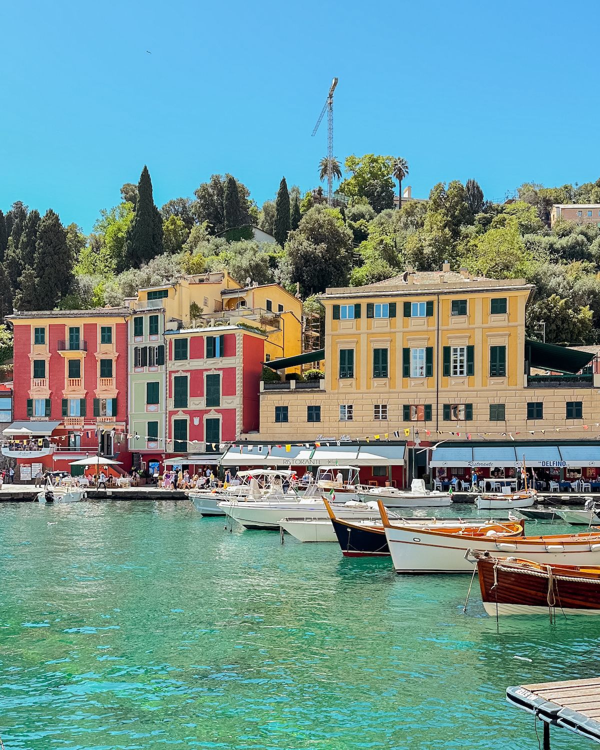 White and brown boats bobbing in turquoise harbour front of Portofino
