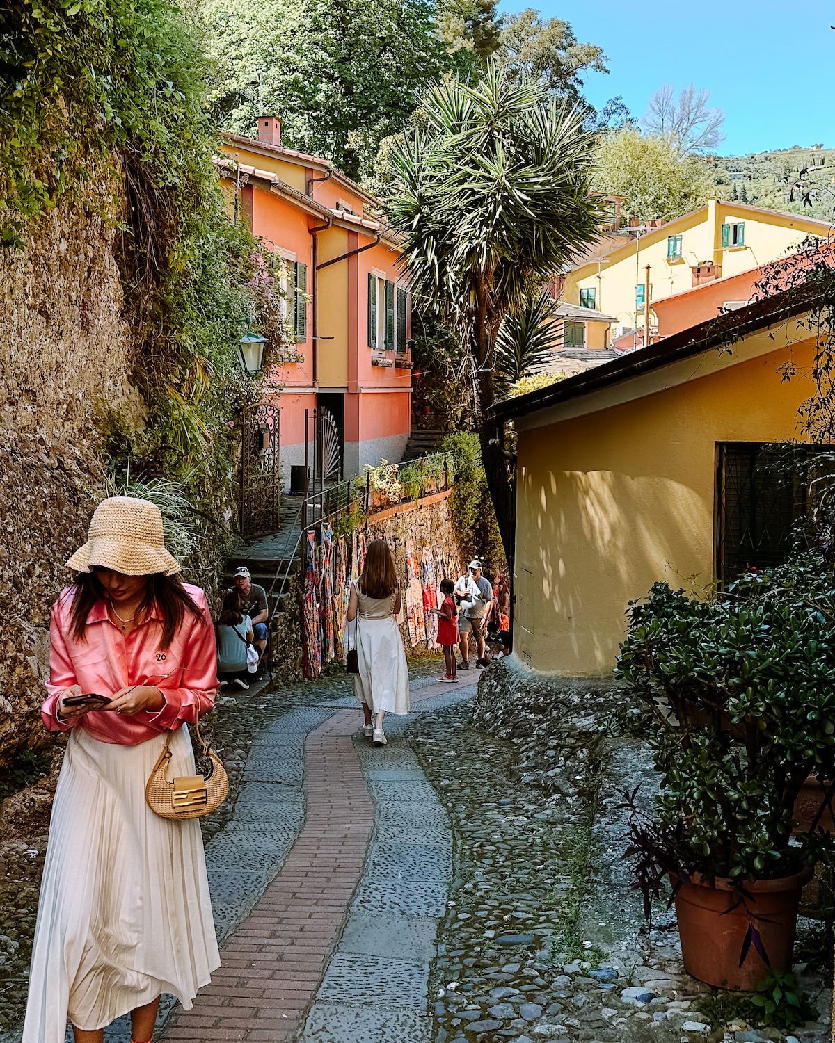 Two girls in dresses walking down a quiet cobblestone pathway in Portofino