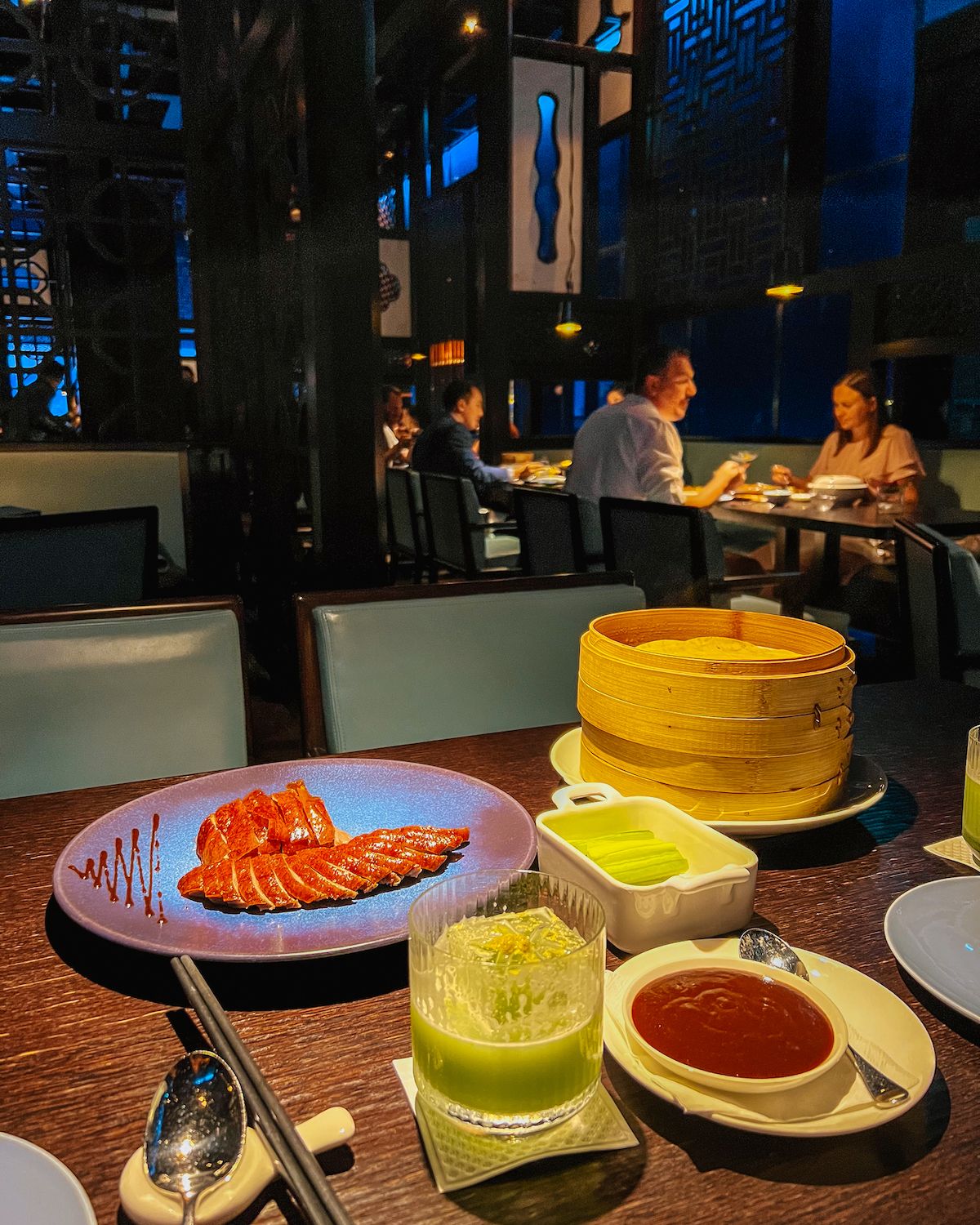 Orange Peking duck and a green cocktail inside the dimly lit Hakkasan Abu Dhabi