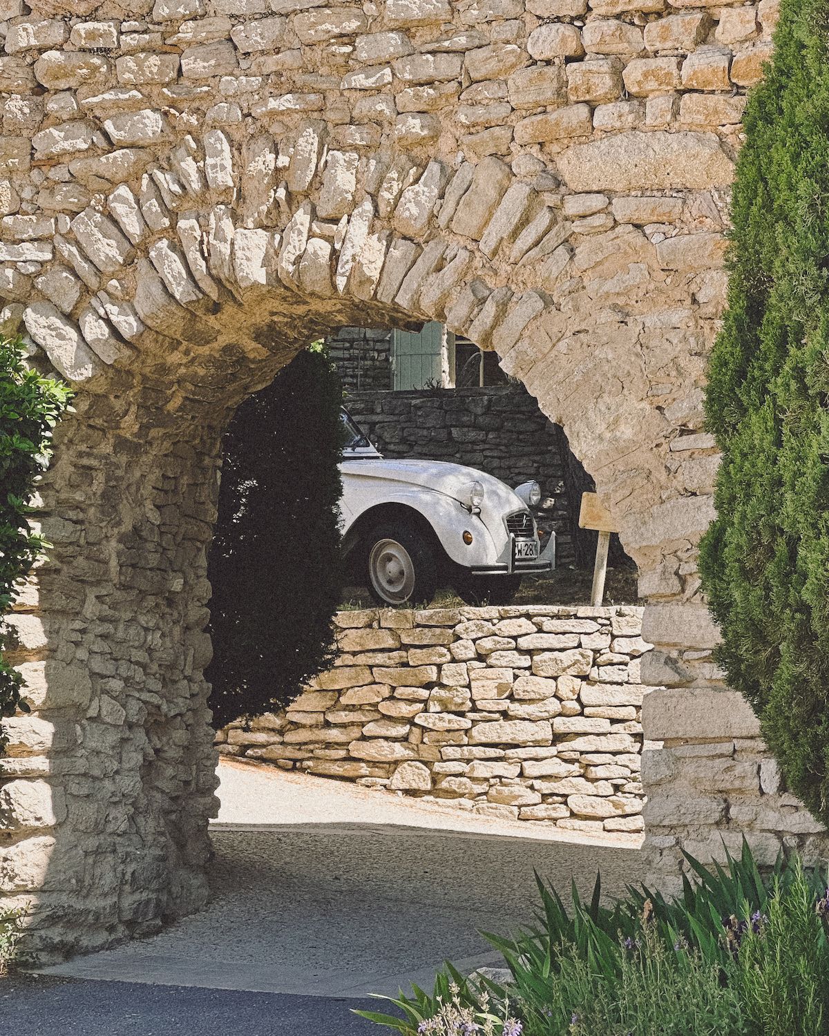 Old white French car under an archway in Provence