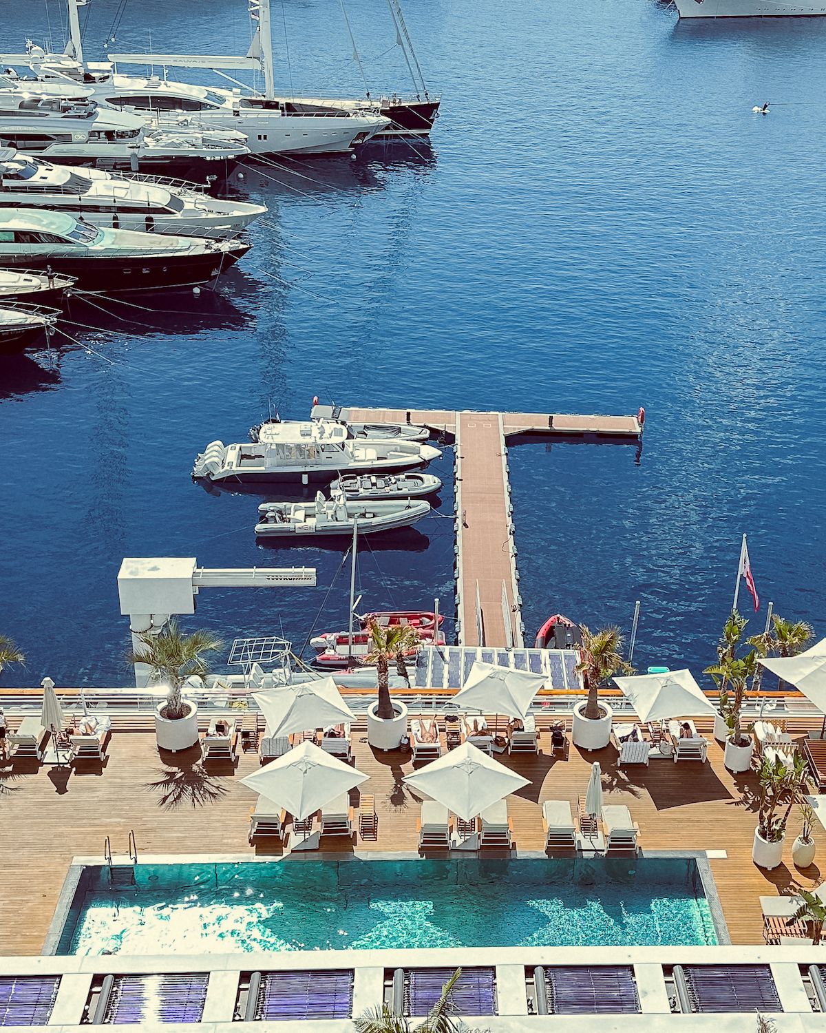 A pool and lounge chairs at a yacht club overlooking Monte Carlo's harbour