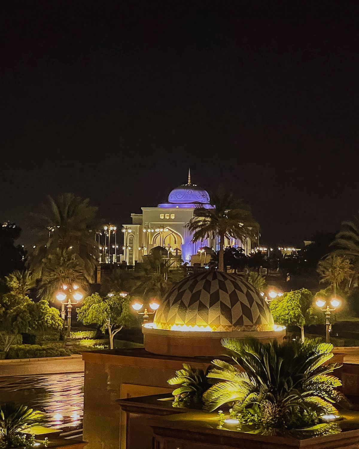 Outside of Emirates Palace Mandarin Oriental with its lit up purple dome at nighttime