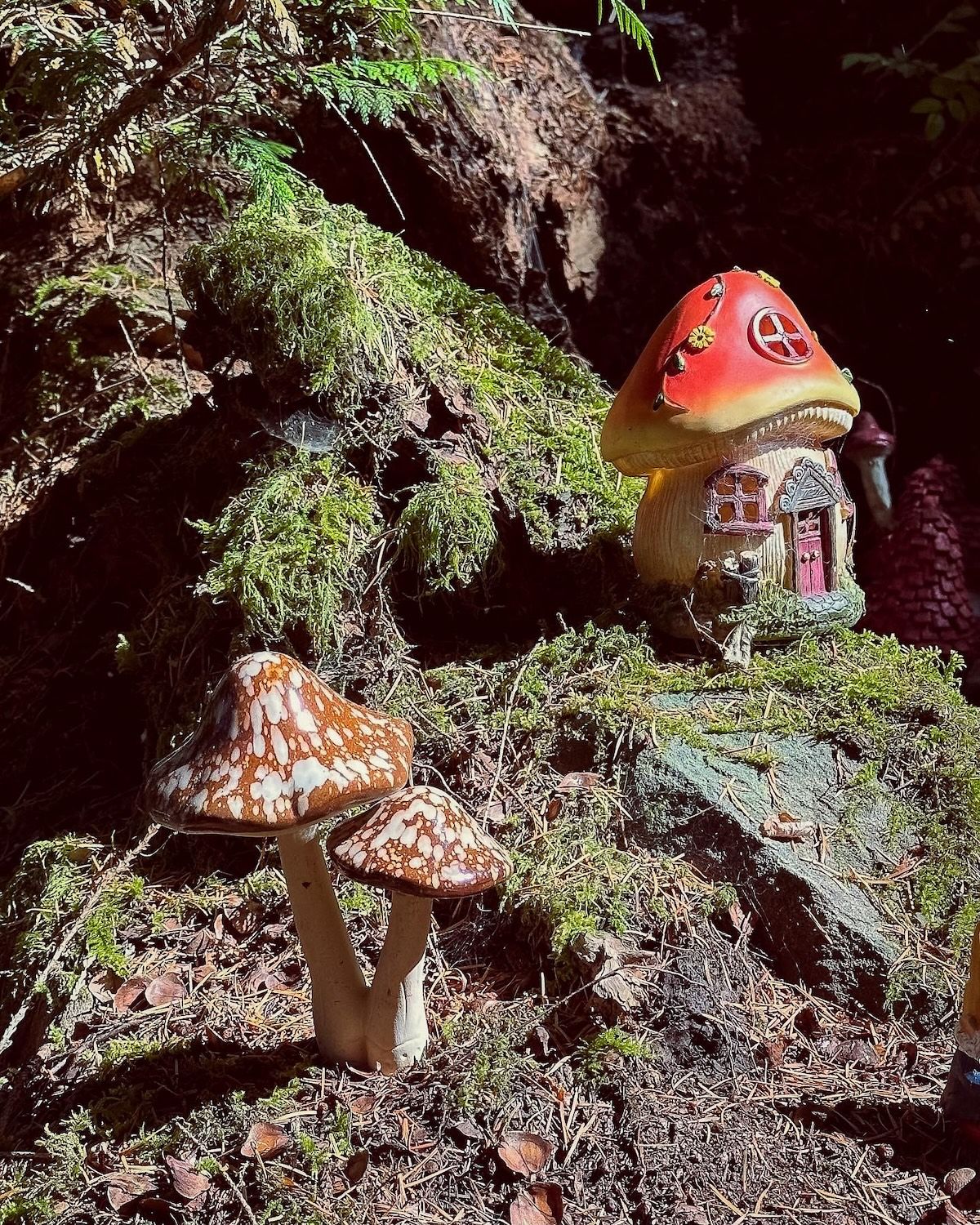Toy mushrooms and mushroom house in moss outside