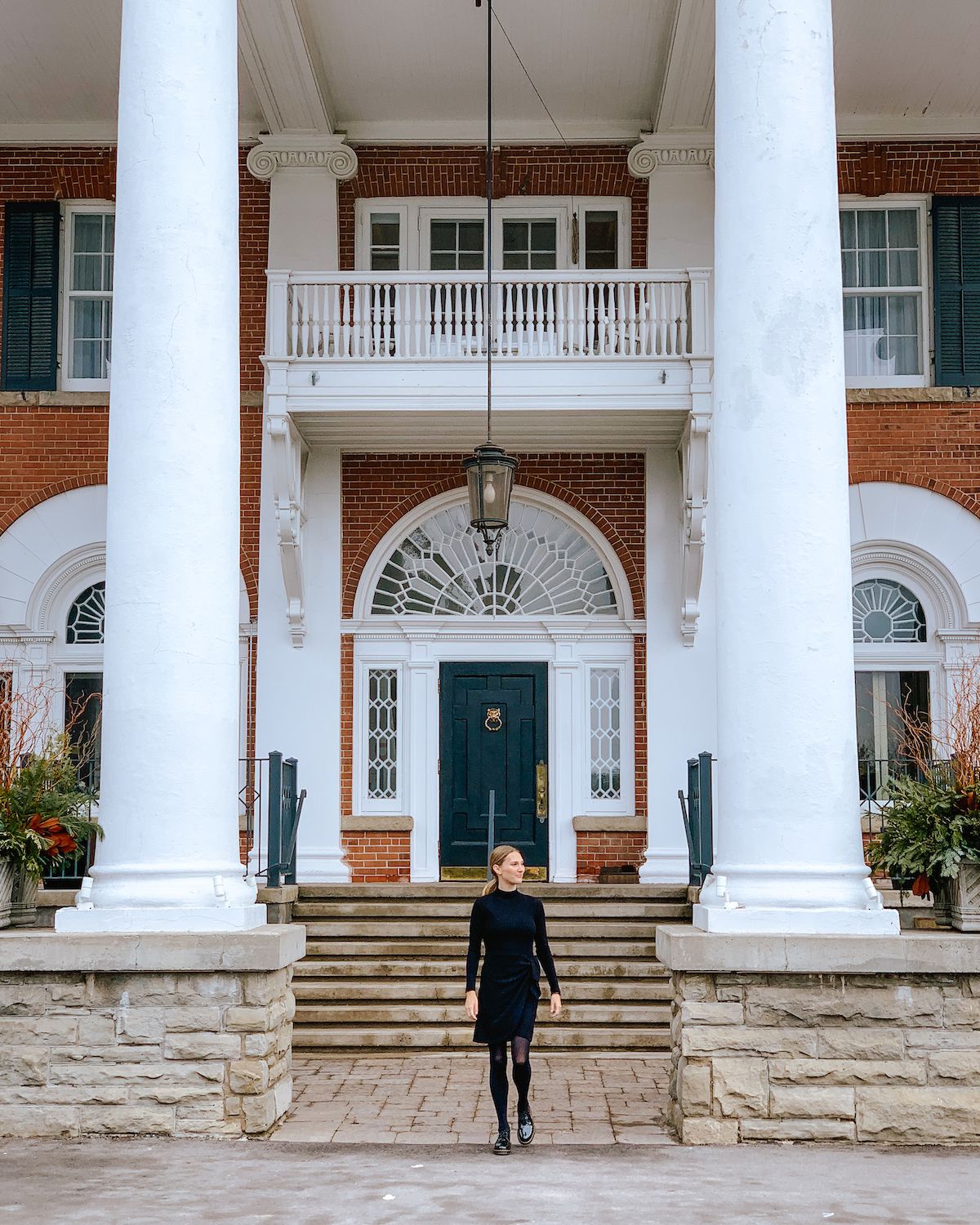 Blonde girl in black dress walking down front door steps of Langdon Hall