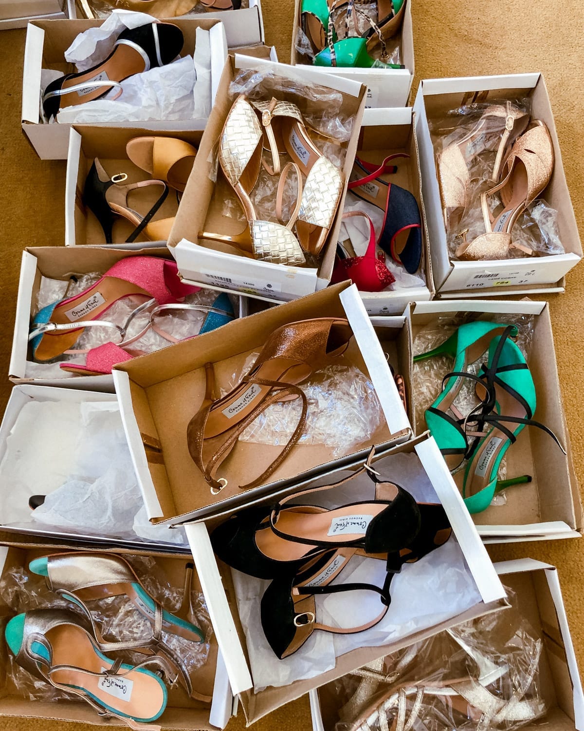 An assortment of glamorous tango shoes in open boxes — glittery, metallic, and bold, ready for a night of dancing.