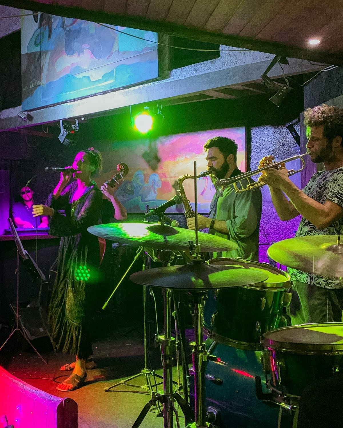 Jazz band with vocals, trumpet, saxophone and keyboard performing under colourful lights at The Maze in Rio.