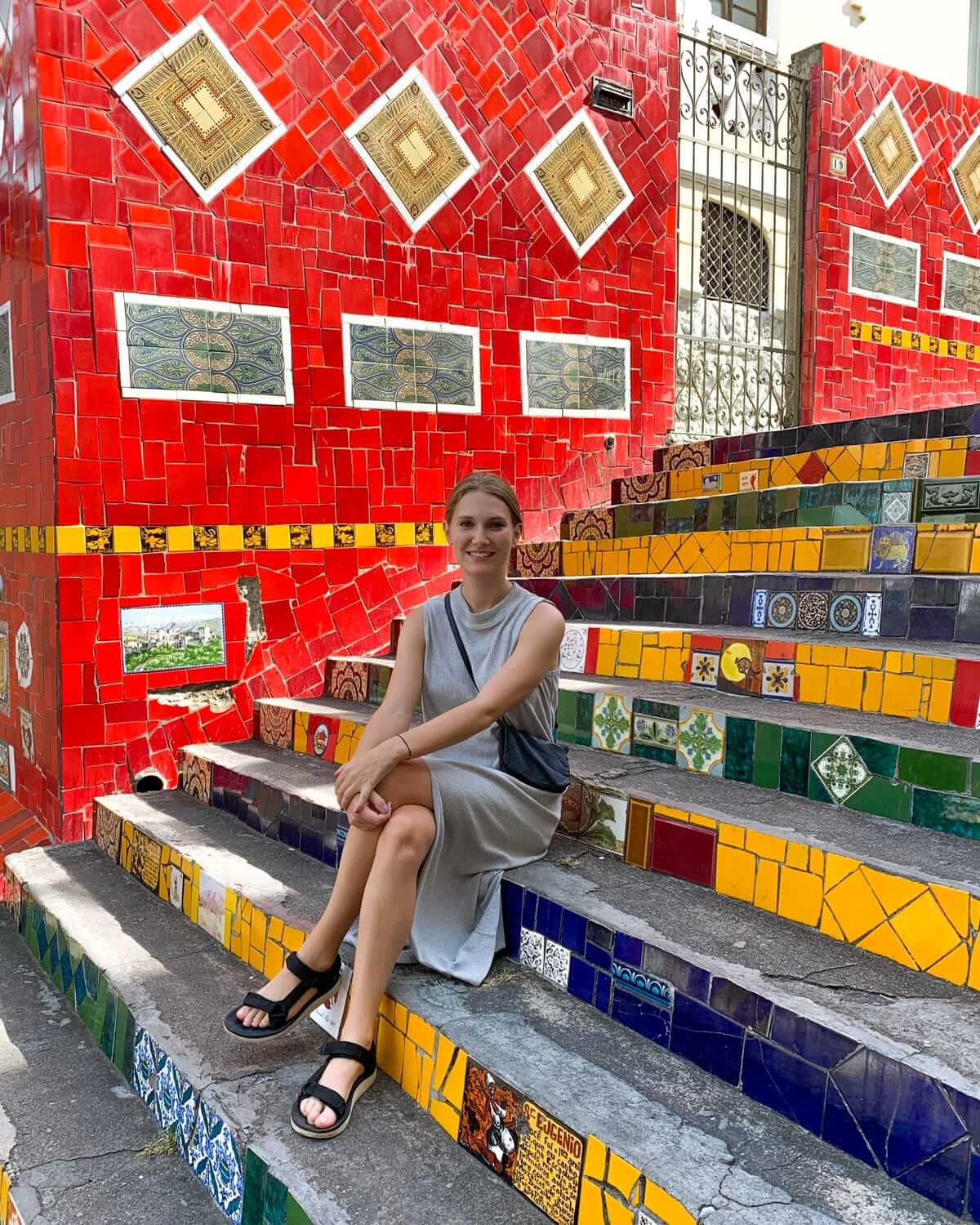 Cec sitting on the vibrant mosaic-tiled Selarón steps, one of the most iconic and Instagrammable spots in Rio de Janeiro for colourful street art.