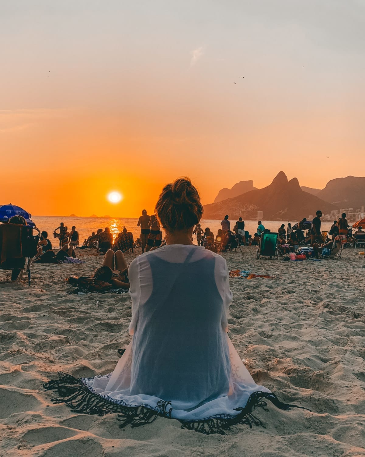 Cec sitting on Ipanema Beach at sunset with the iconic Two Brothers Mountain in the distance.