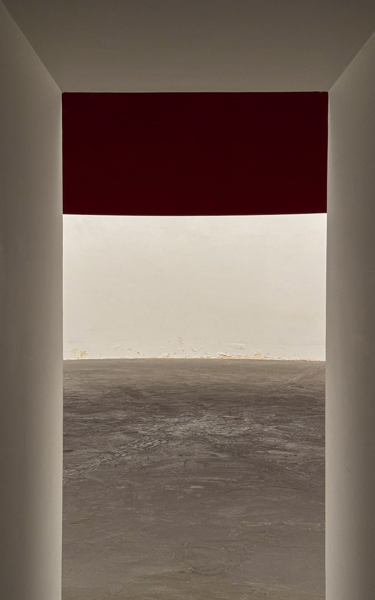 Entrance to Minimalist installation by Anish Kapoor, with clean white walls, a dramatic red horizontal panel, and a polished concrete floor inside Kanaal gallery.
