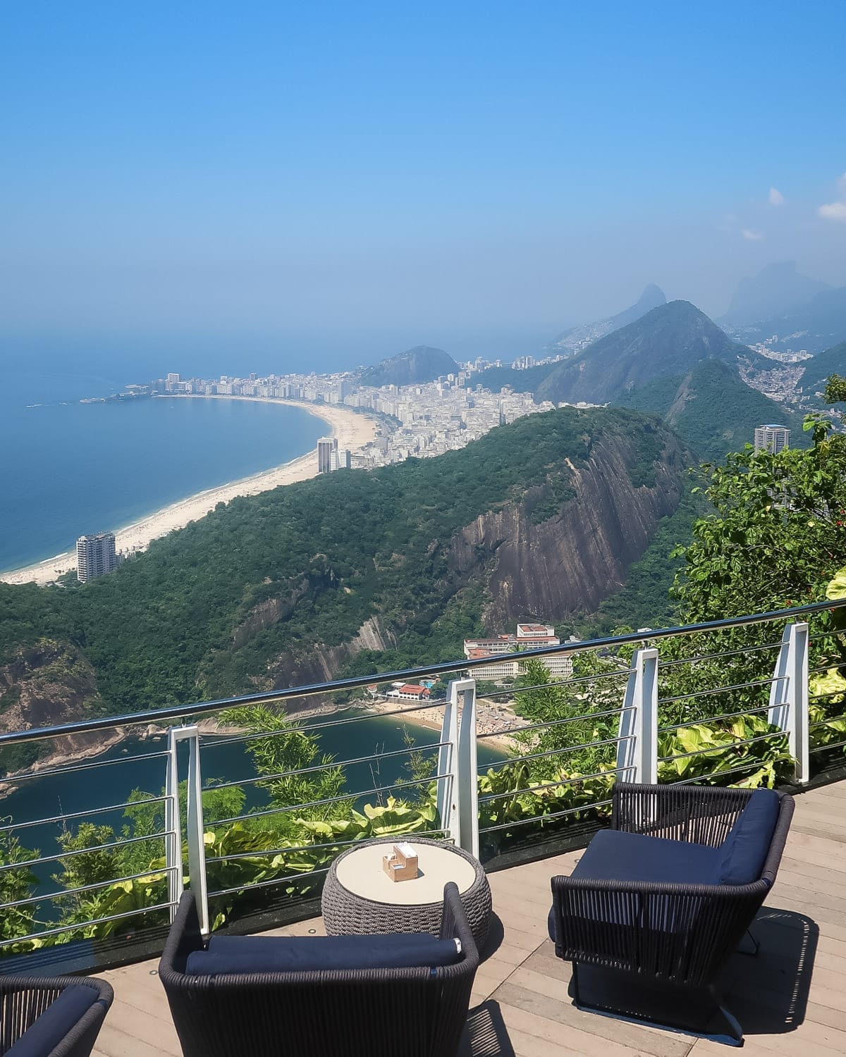 Lounge chairs overlooking Praia Vermelha and Copacabana Beach from the Sugarloaf Mountain bar deck, offering one of the best views in Rio de Janeiro.