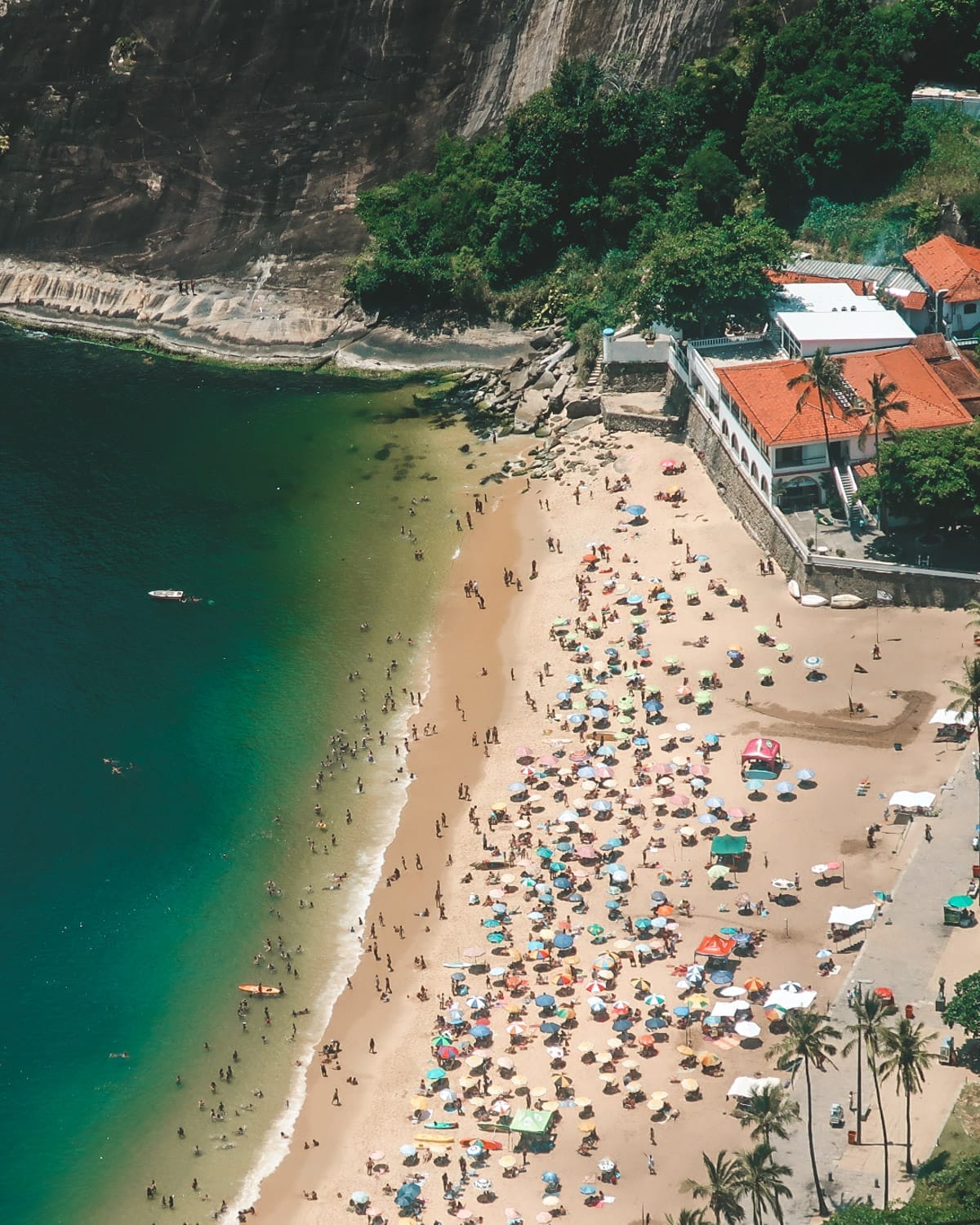 Aerial view of Praia Vermelha with colorful umbrellas lining the beach and cliffs rising behind it, capturing one of Rio de Janeiro’s most photogenic beaches.