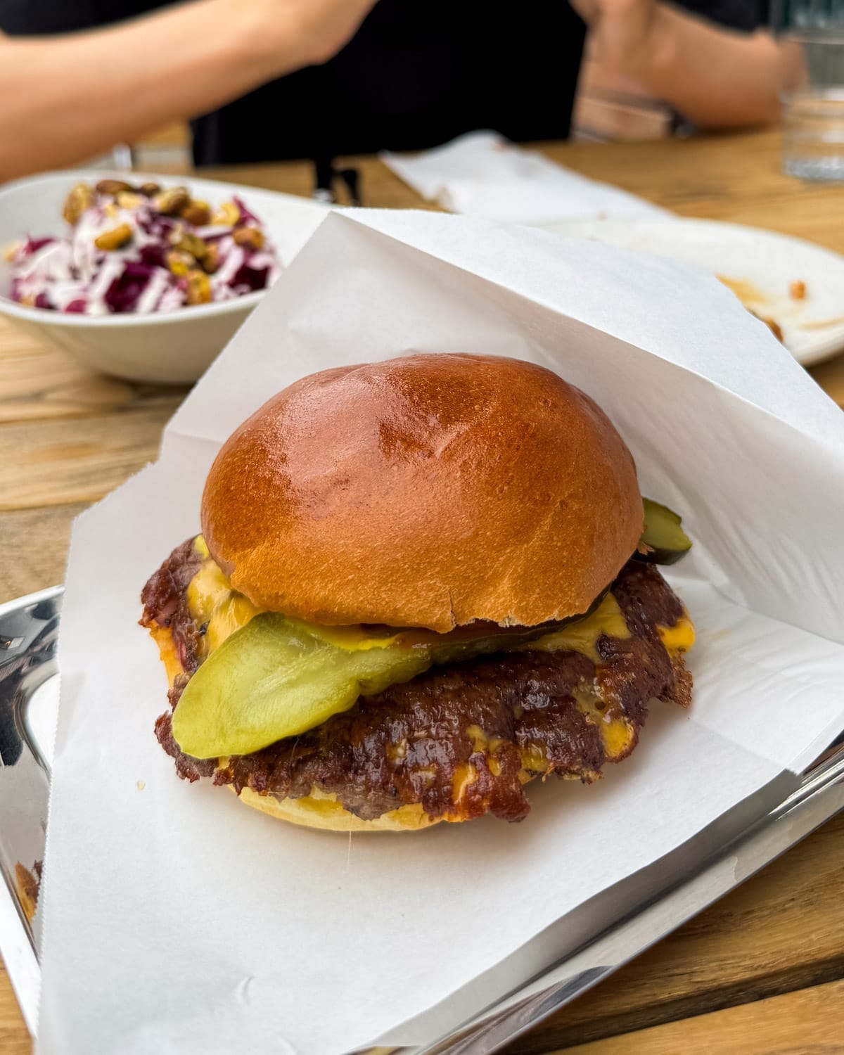 Close-up of a juicy smash burger with melted cheese and pickles on a brioche bun from Plump Antwerp.