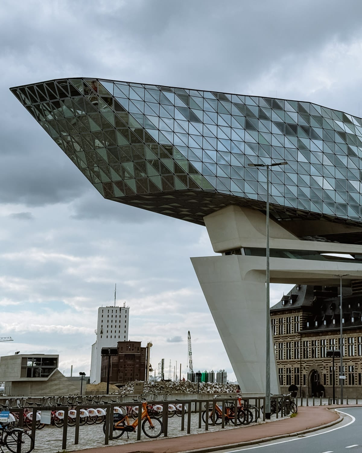 Modern glass and steel Port House structure perched atop a historic building, set against an overcast industrial skyline.