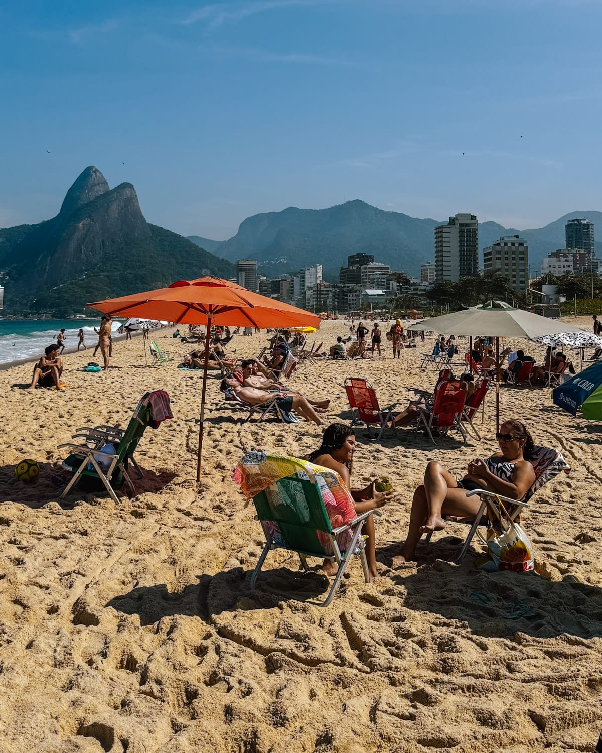 Beachgoers on Leblon Beach sitting in beach chairs.
