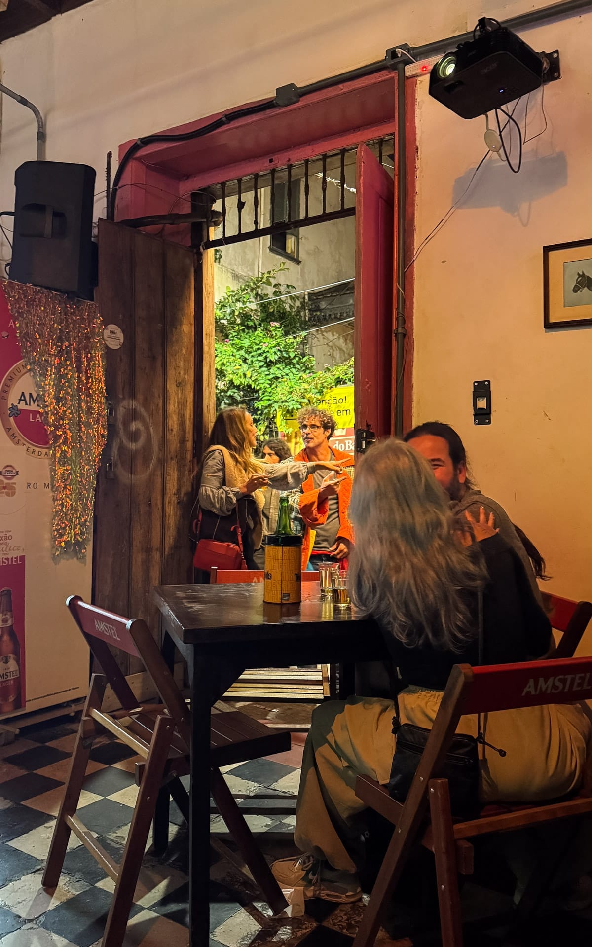 Friends chatting at the doorway of Bar Novooeste, small groups enjoying drinks inside.