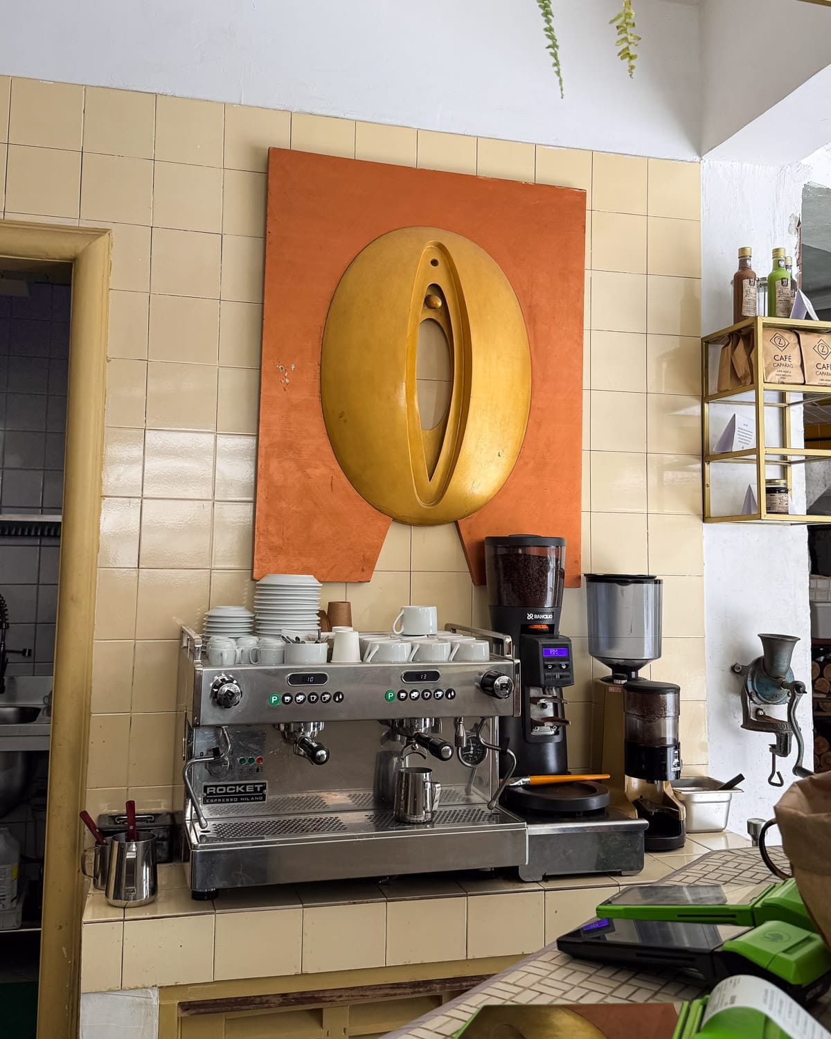 PropereEspresso machine under contemporary yellow wall art at Zola Pizza, a hidden gem for coffee lovers seeking non-touristy spots in Rio.