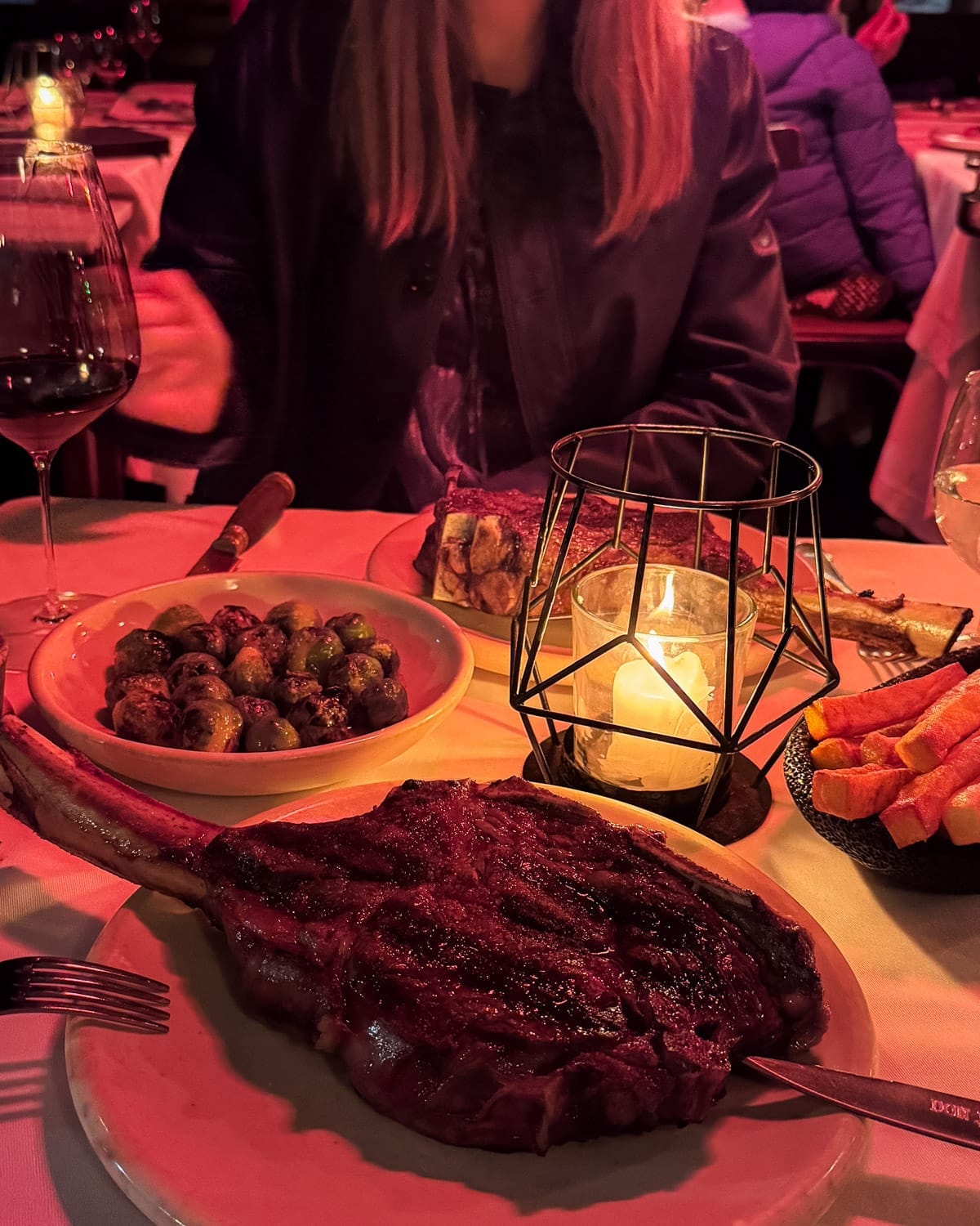 Grilled tomahawk steak with sides of brussels sprouts and fries, served by candlelight at Don Julio..