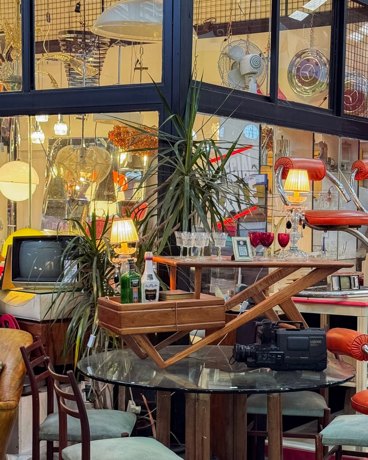 Colourful interior with retro furniture, lamps, a typewriter, and glassware at Mercado de las Pulgas.