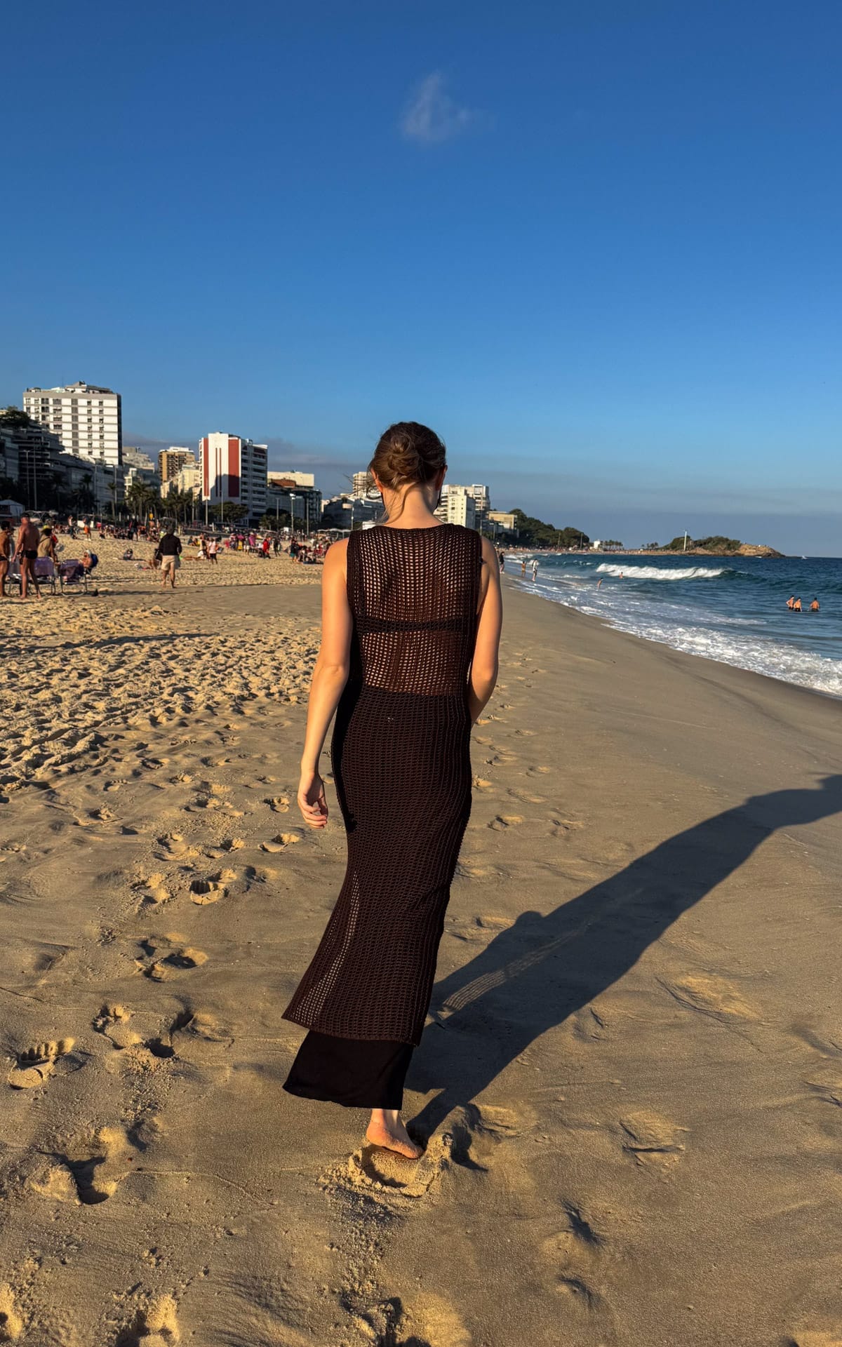 Cec in a net dress from Haight walking barefoot along a golden Ipanema Beach at sunset.