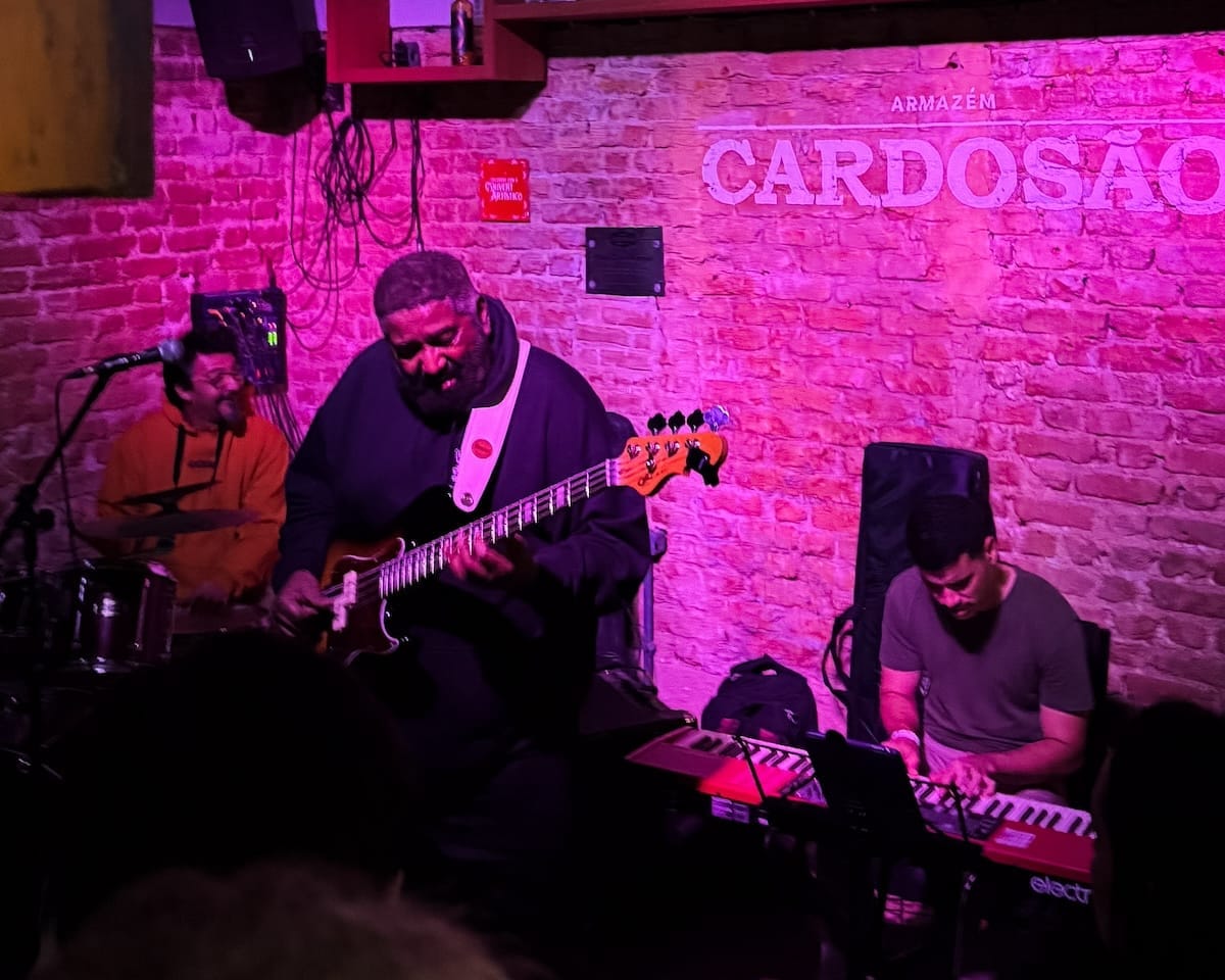 Live band playing guitar, keyboard, and drums inside Armazém Cardosão in Rio, known for its intimate, local music scene.