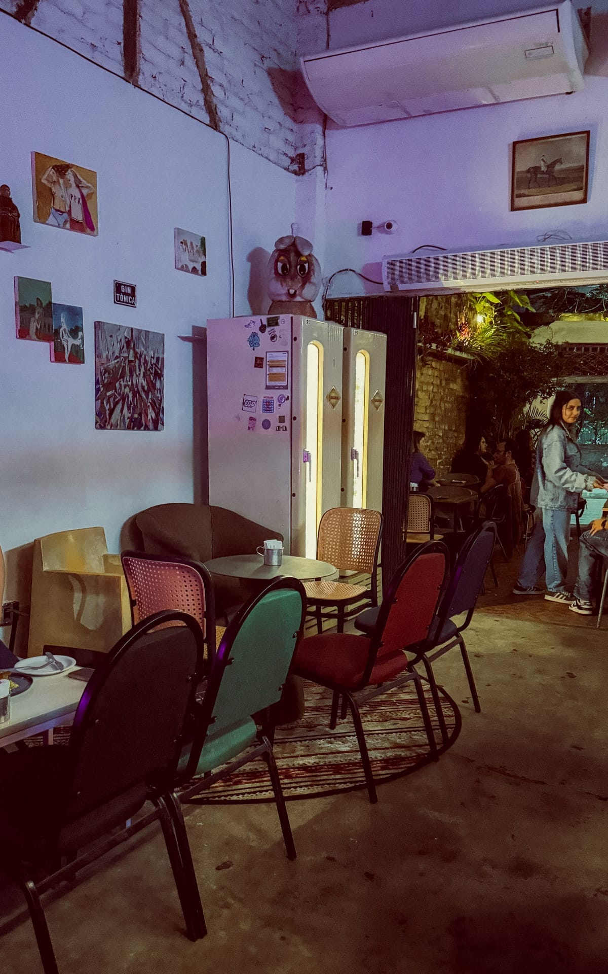 Eclectic interior of Quartinhi Bar with mismatched chairs and erotic wall art.