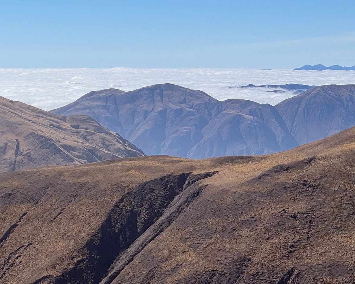 Golden-brown mountain ridges rising above a sea of clouds along the high-altitude road from Salta to Cachi.