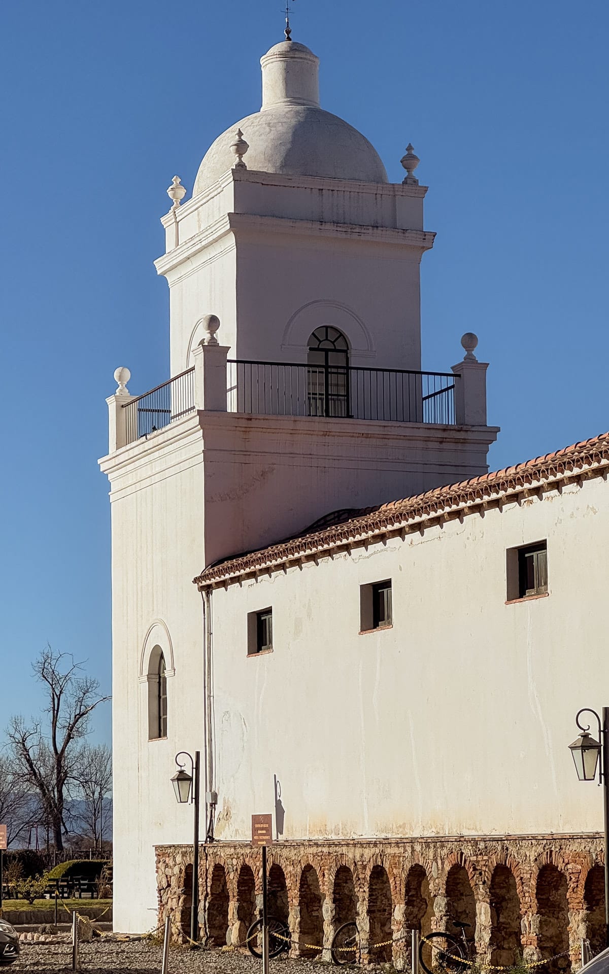 Whitewashed colonial bell tower at El Esteco Winery with arched base and red-tiled roof.