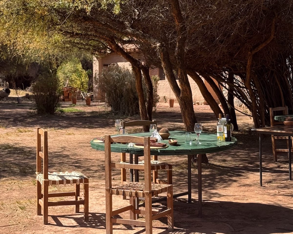 Rustic table set for lunch with wine under shady trees at a Santa Elena ranch.