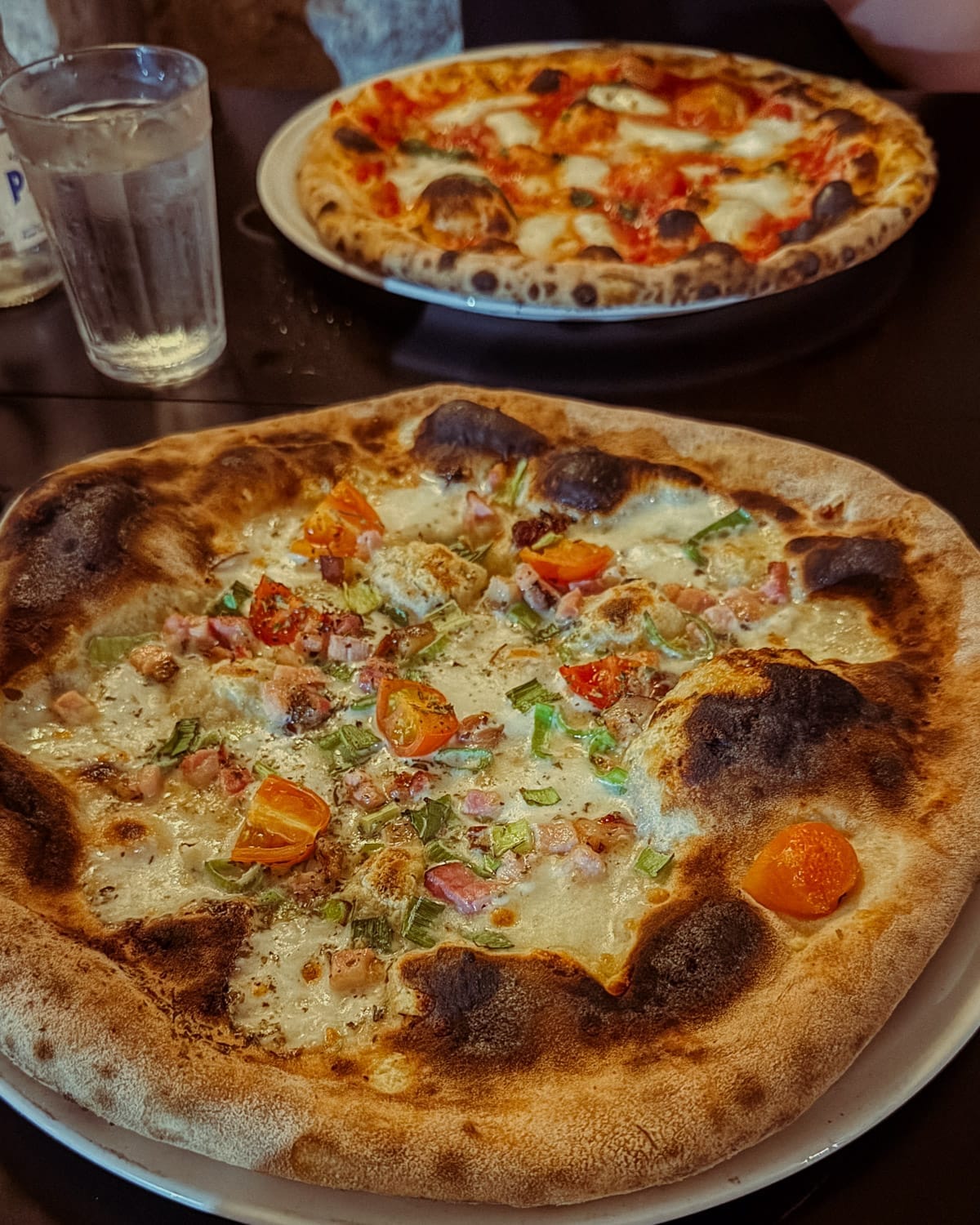 Close-up of two Neapolitan-style pizzas on a table at Zola Pizza.