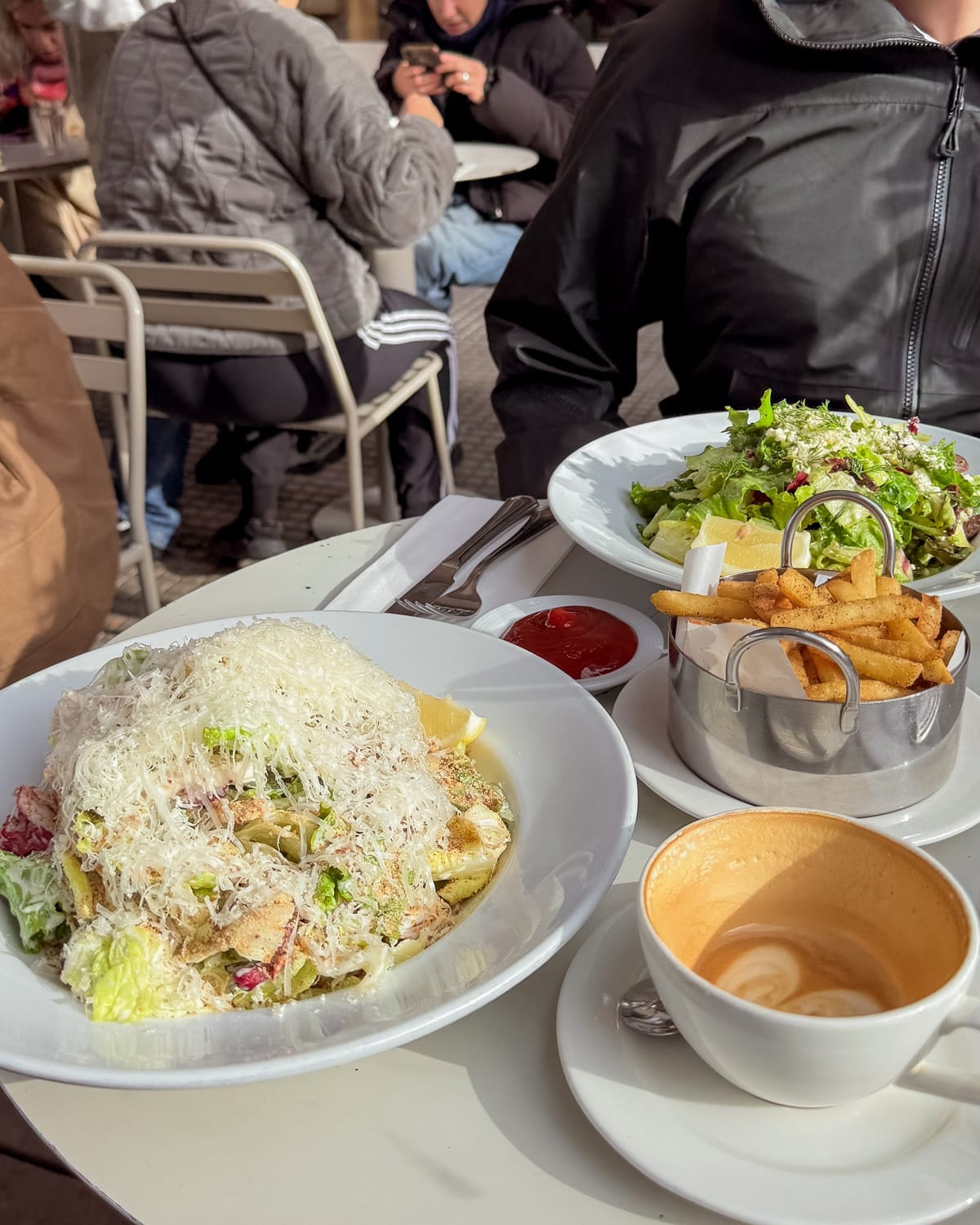 Two plates of salad with fries and coffee on an outdoor table at Oli Cafe in Buenos.