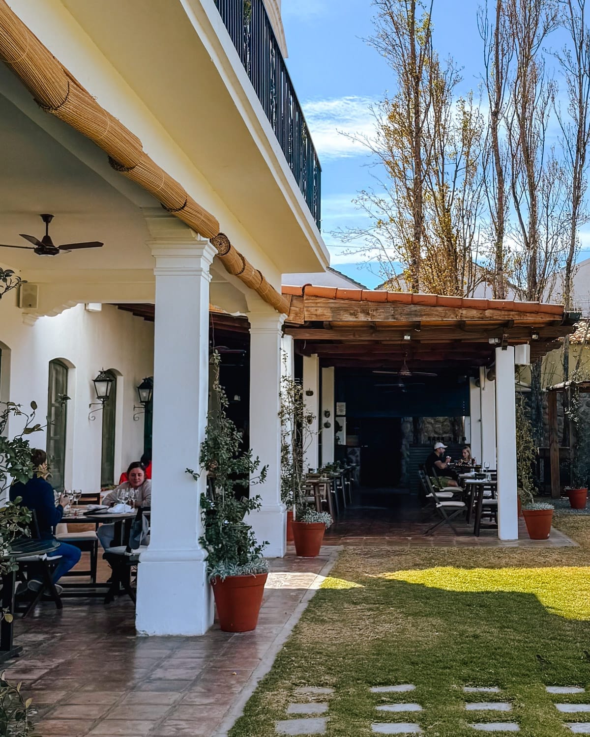 Outdoor dining patio at Patios de Cafayate Wine Hotel with white colonial columns and terracotta tiles under a sunny sky.