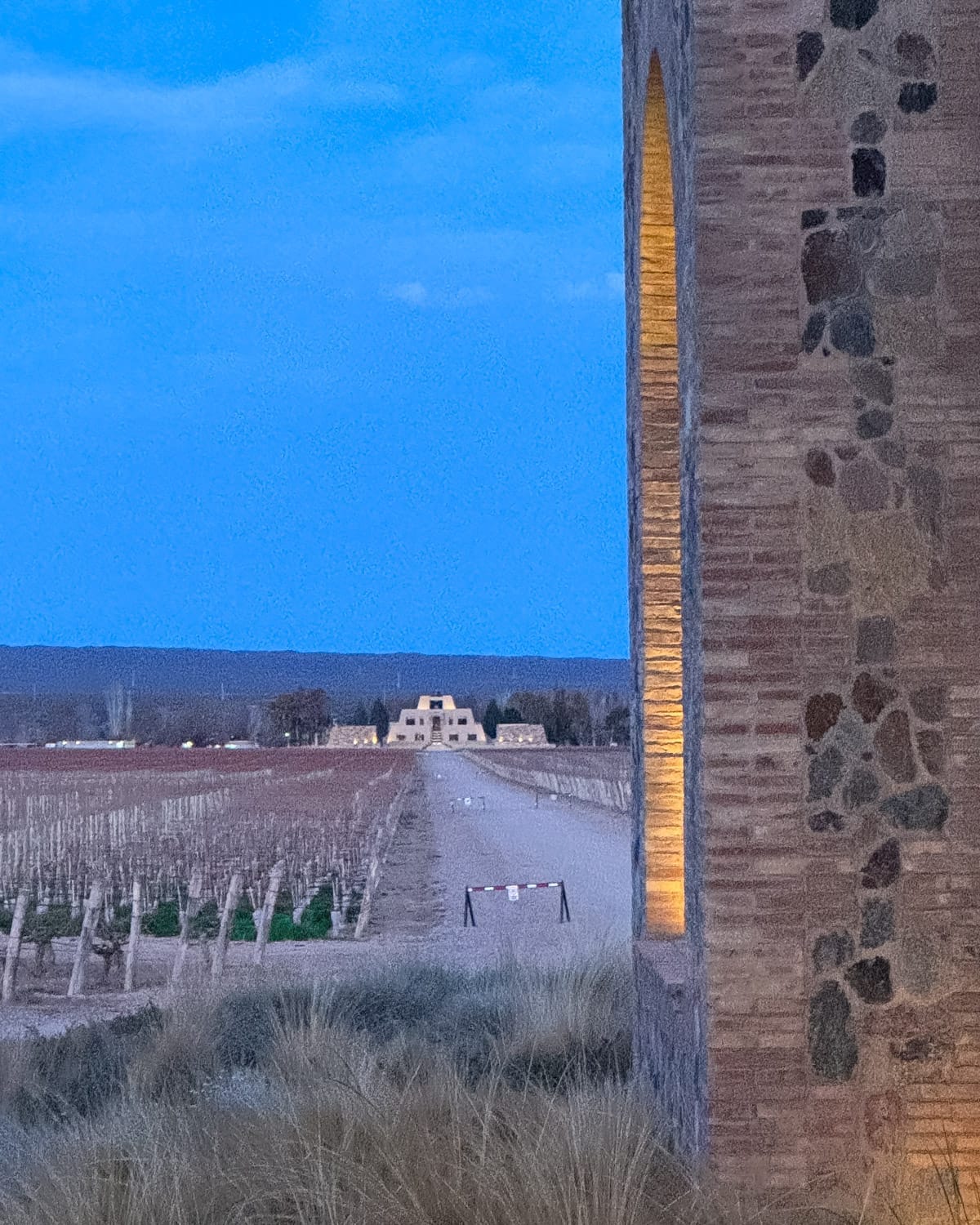 Evening view of Catena Zapata's pyramid winery in the distance with vineyards.
