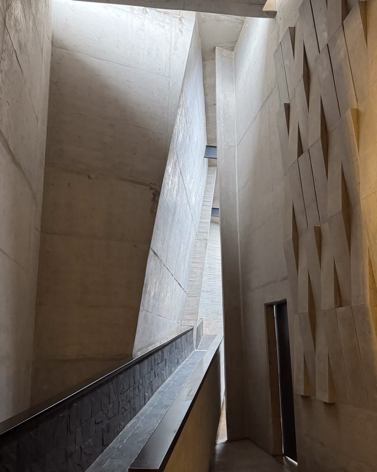 Angular concrete hallway inside Bodega Zuccardi, with dramatic light and geometric architectural details.