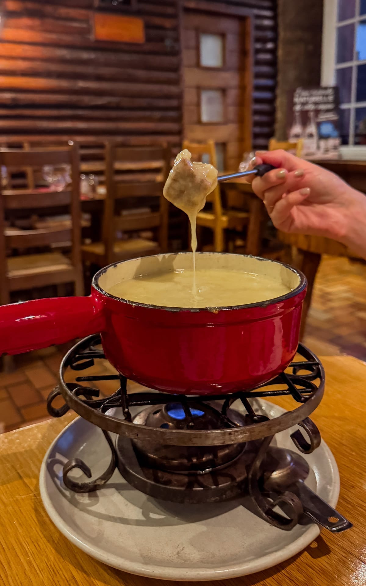 Comté cheese fondue bubbling in a red pot at La Finette, a traditional tavern in Arbois.