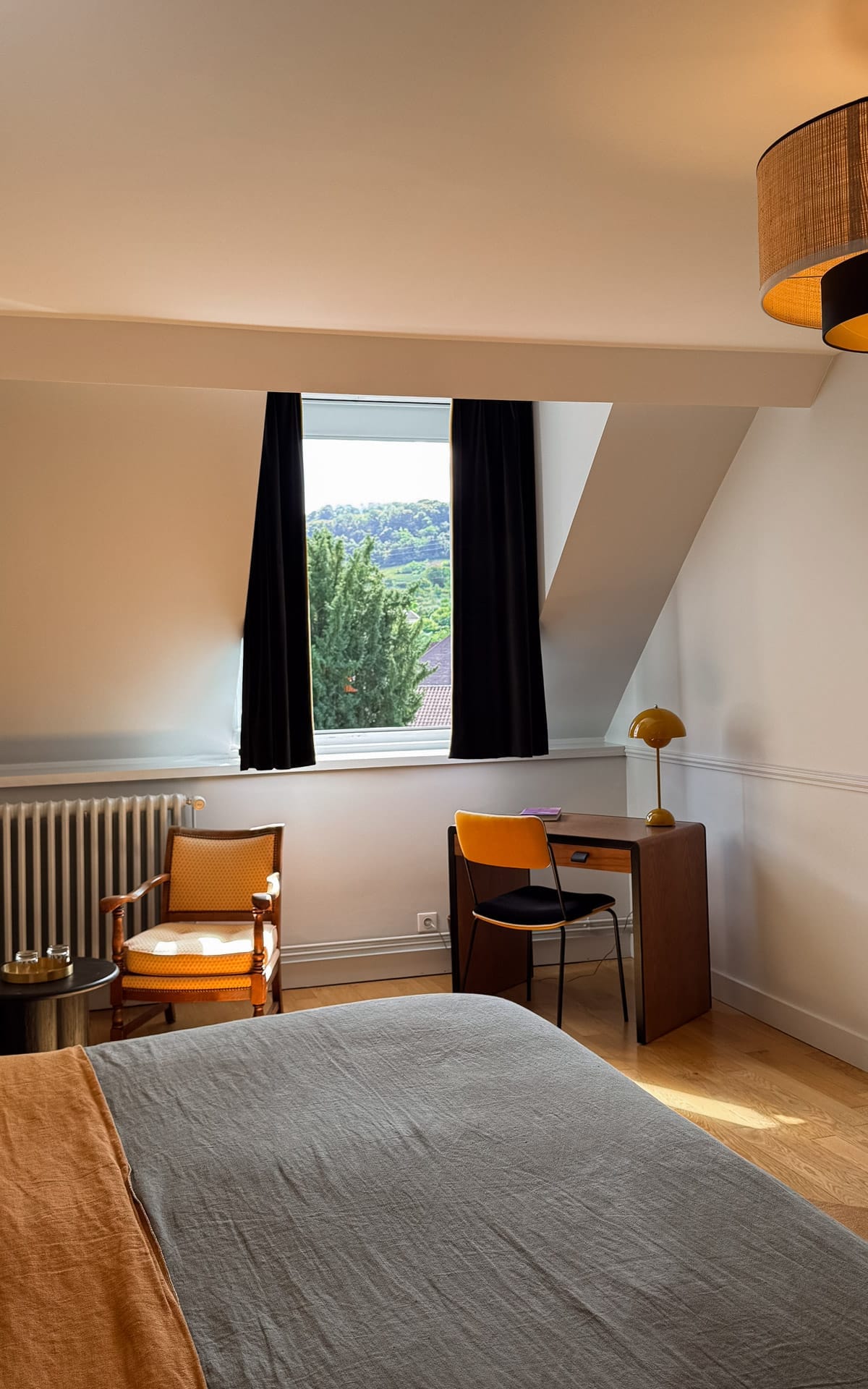Minimalist guest room at La Closerie des Capucines with desk, armchair, and countryside view.