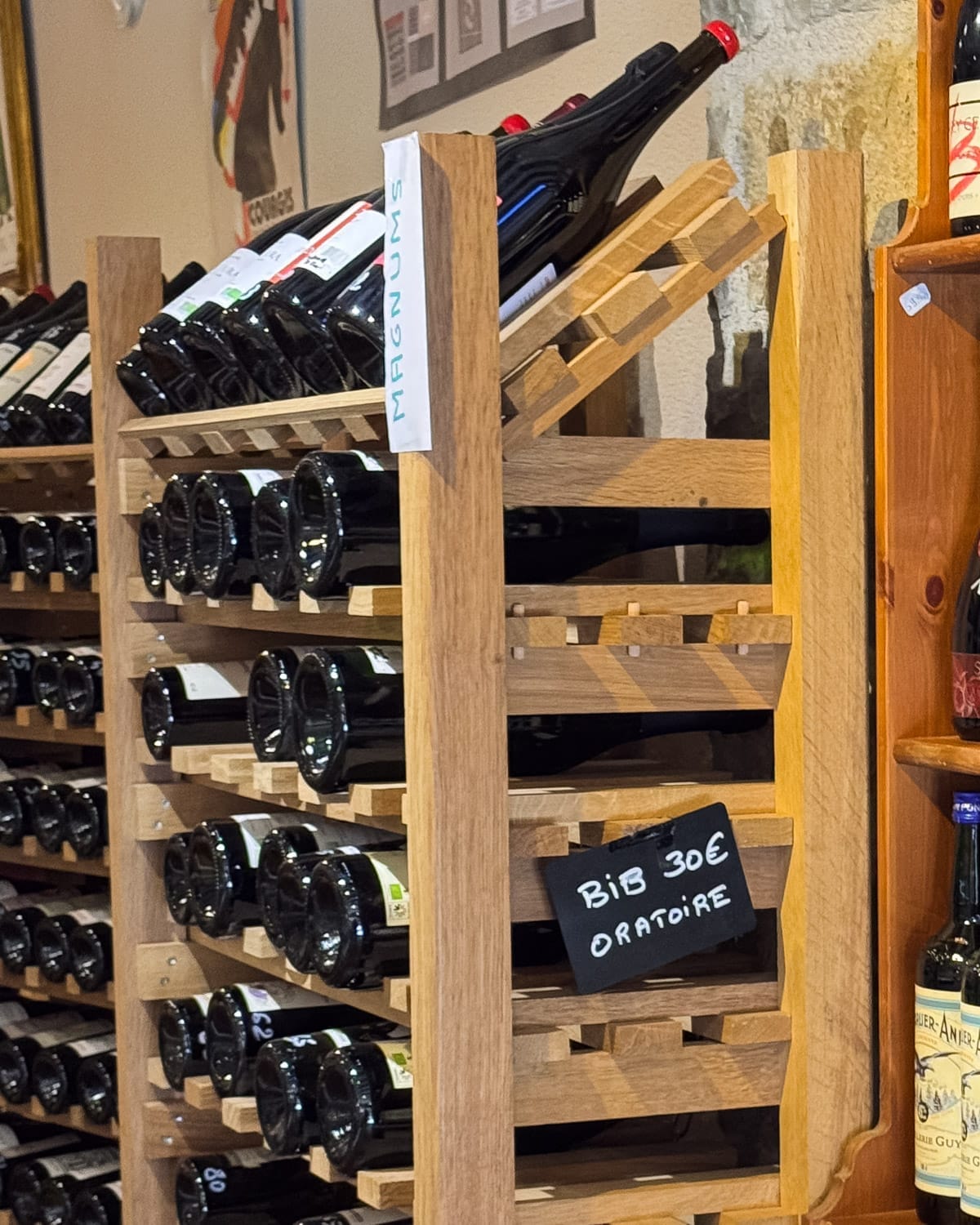 Jura wine bottles displayed on wooden racks inside an Arbois wine shop.