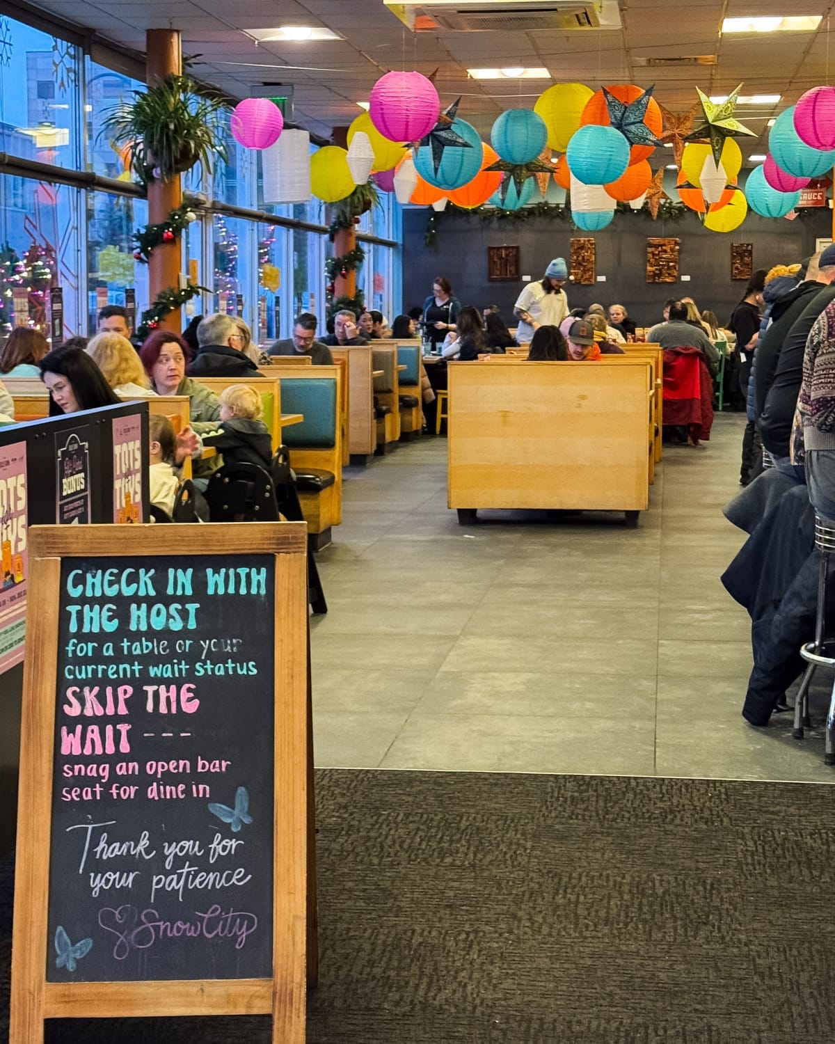Interior of Snow City Cafe in Anchorage, filled with diners in booths beneath colourful hanging lanterns.