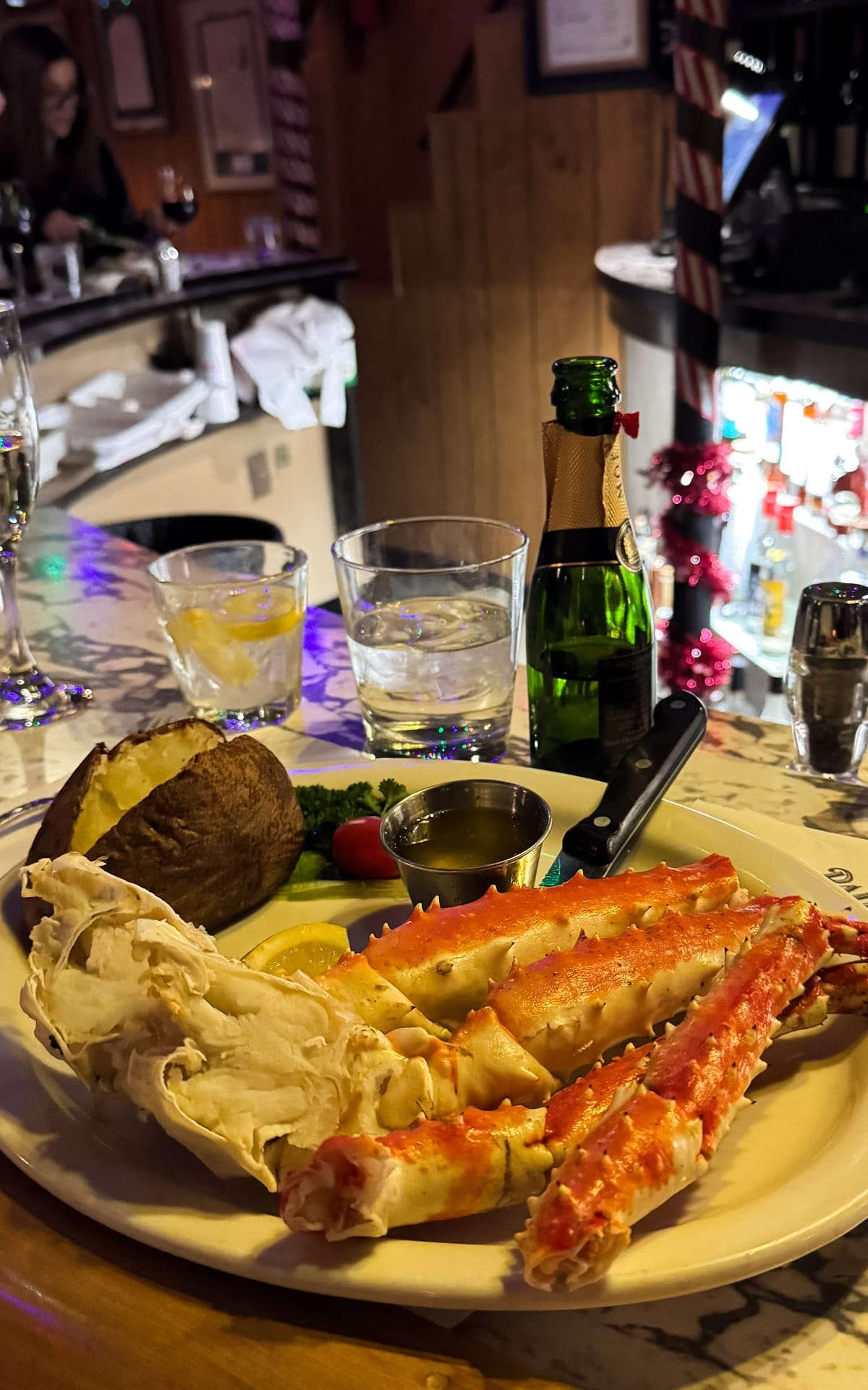 Alaskan king crab legs with baked potato and melted butter served at a marble bar at Club Paris in Anchorage.