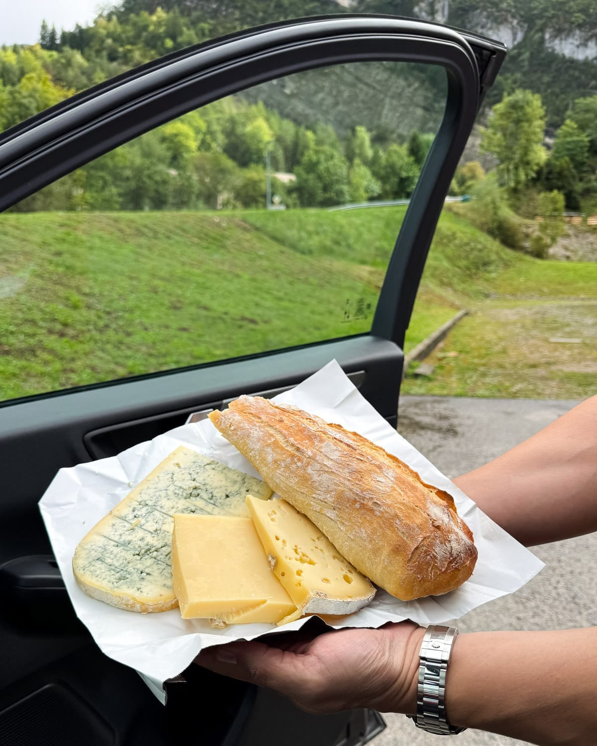 Roadside picnic of Comté cheese, Bleu de Gex, and baguette during a Jura road trip.