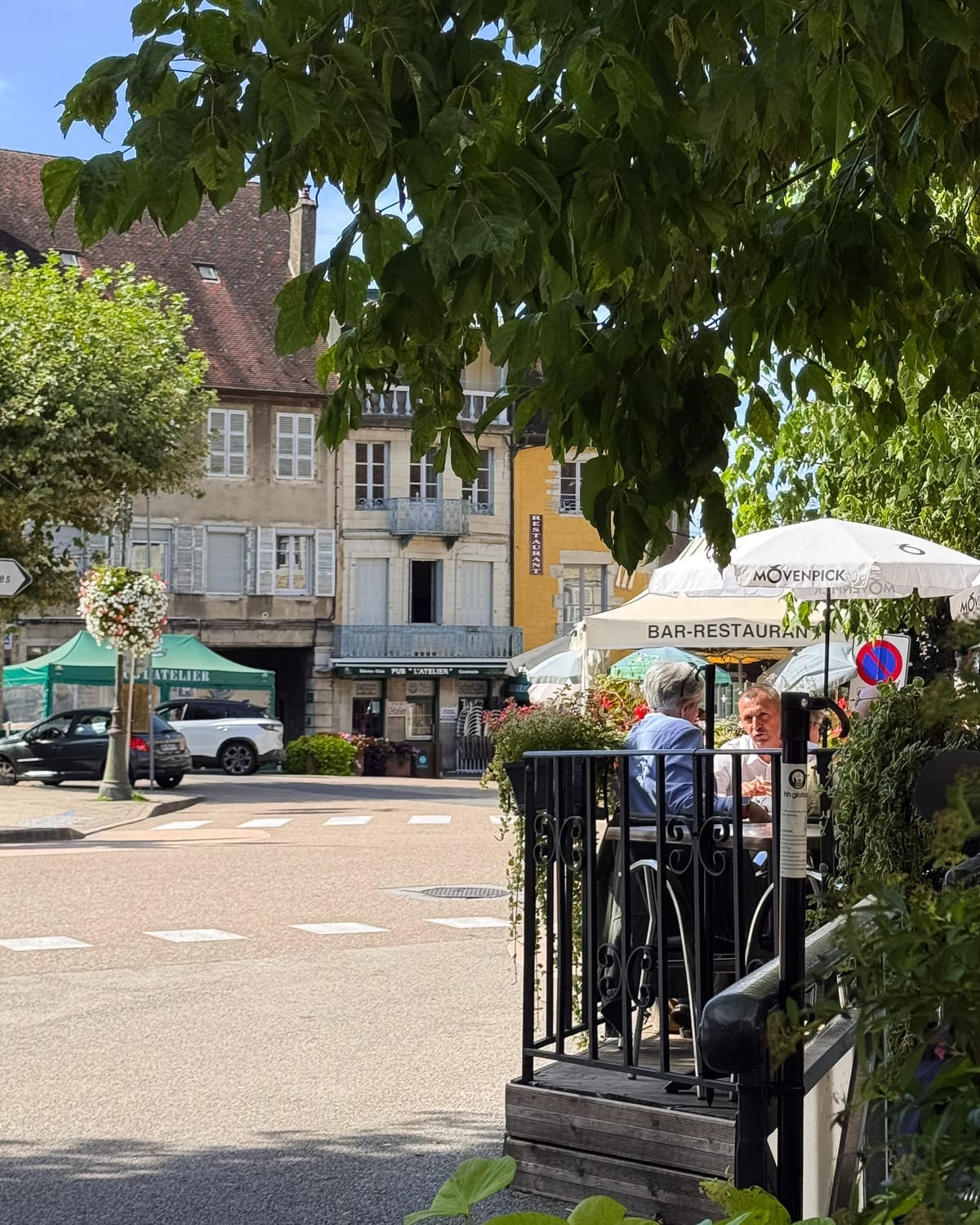 Outdoor café seating in Poligny's town square on a sunny afternoon.