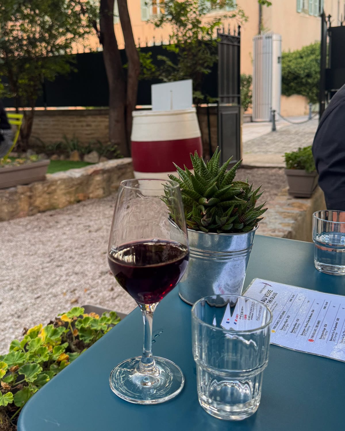 Glass of red Burgundy wine on a courtyard table at Caveau de Dégustation Vins de Bourgogne du Domaine Loubet-Dewailly.