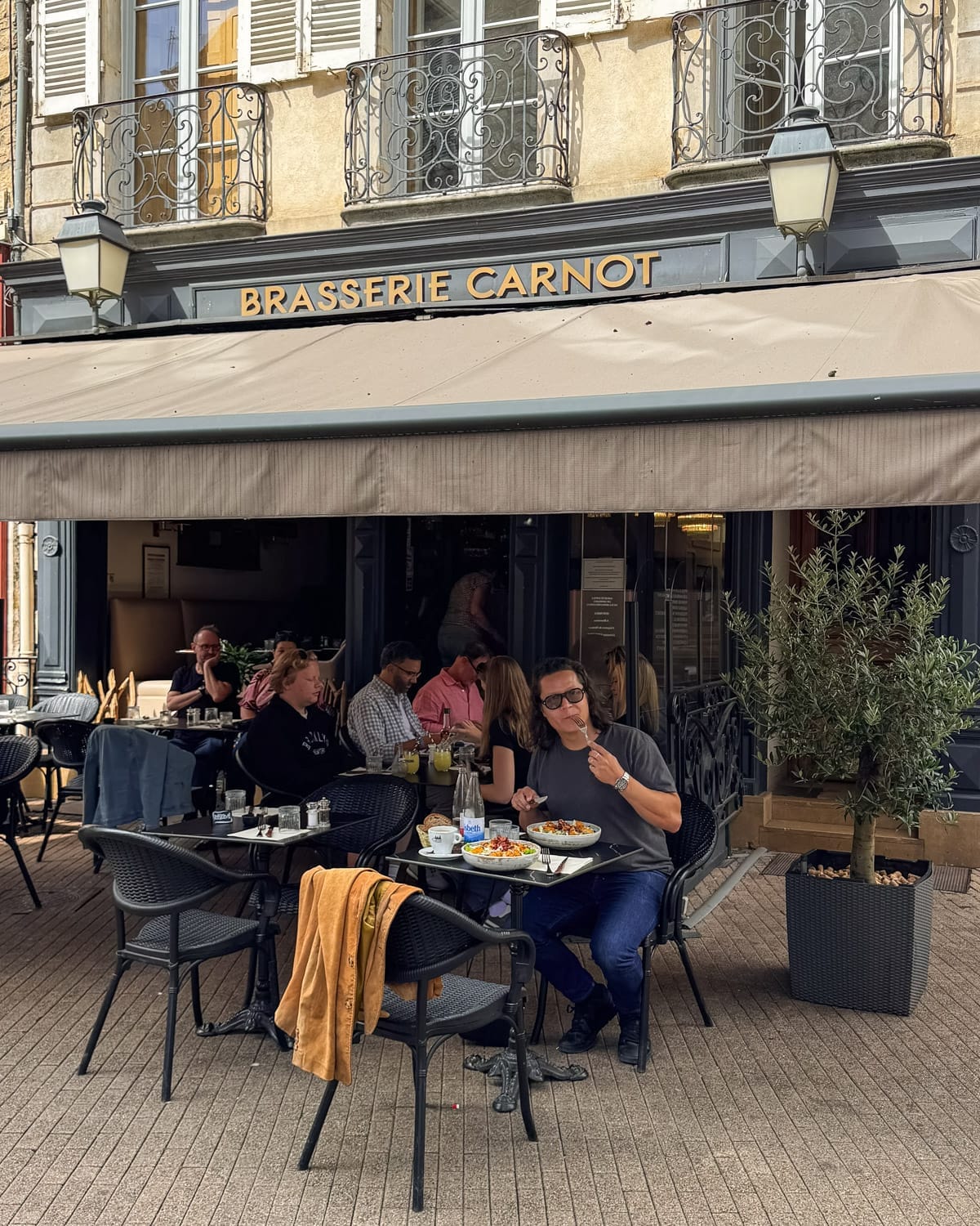 Ari dining at an outdoor table for lunch at Brasserie Carnot in Beaune's historic centre.