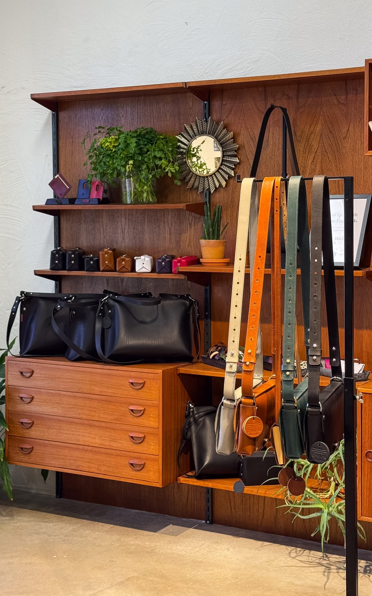 Minimalist leather handbags and wallets on mid-century wooden shelving at Stella Soomlais.
