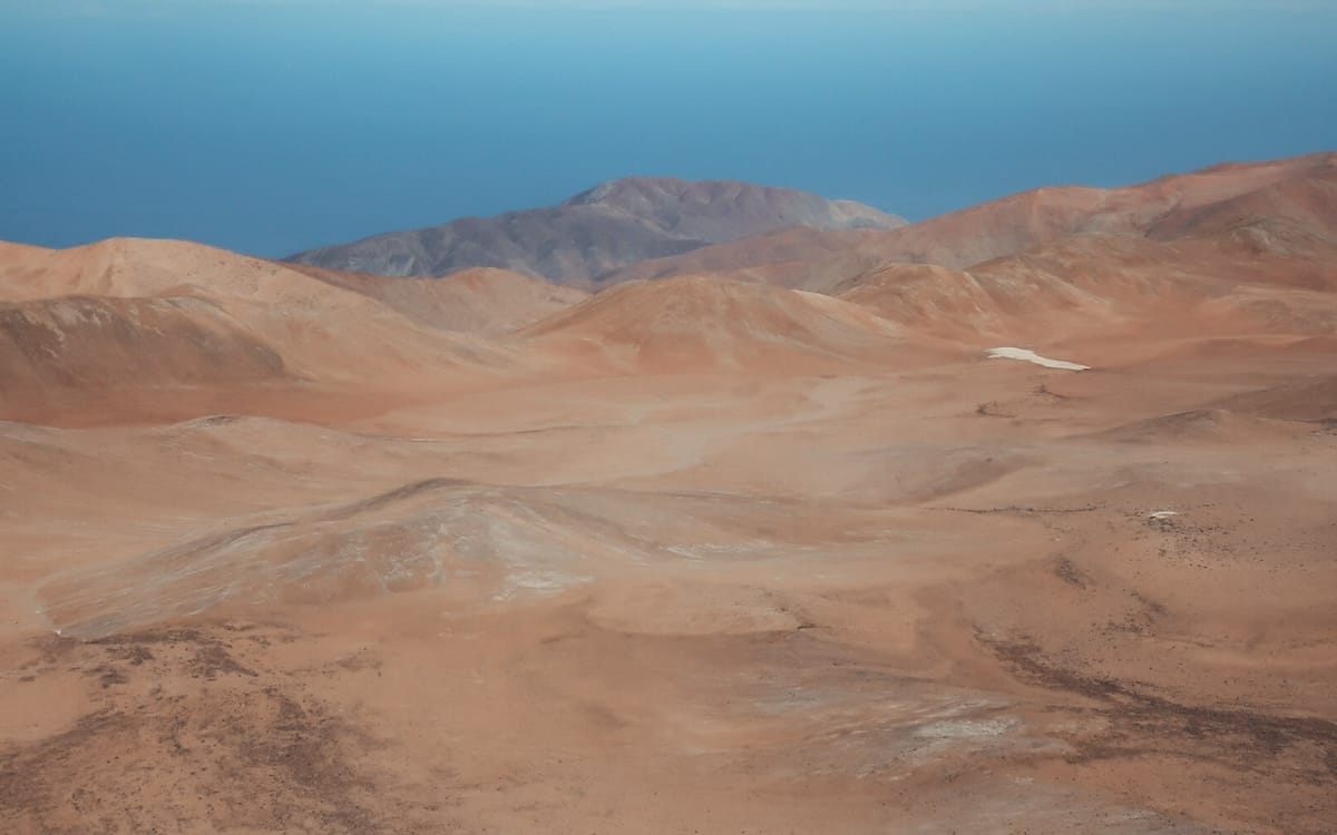 Rolling, rust-coloured dunes spread across Chile’s Atacama Desert, one of South America's amazing travel destinations.