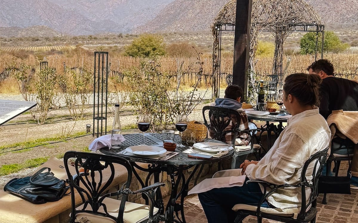 Ari enjoying lunch with red wine on Piattelli Vineyard's terrace overlooking the Andes, one of the best things to do in Cafayate.